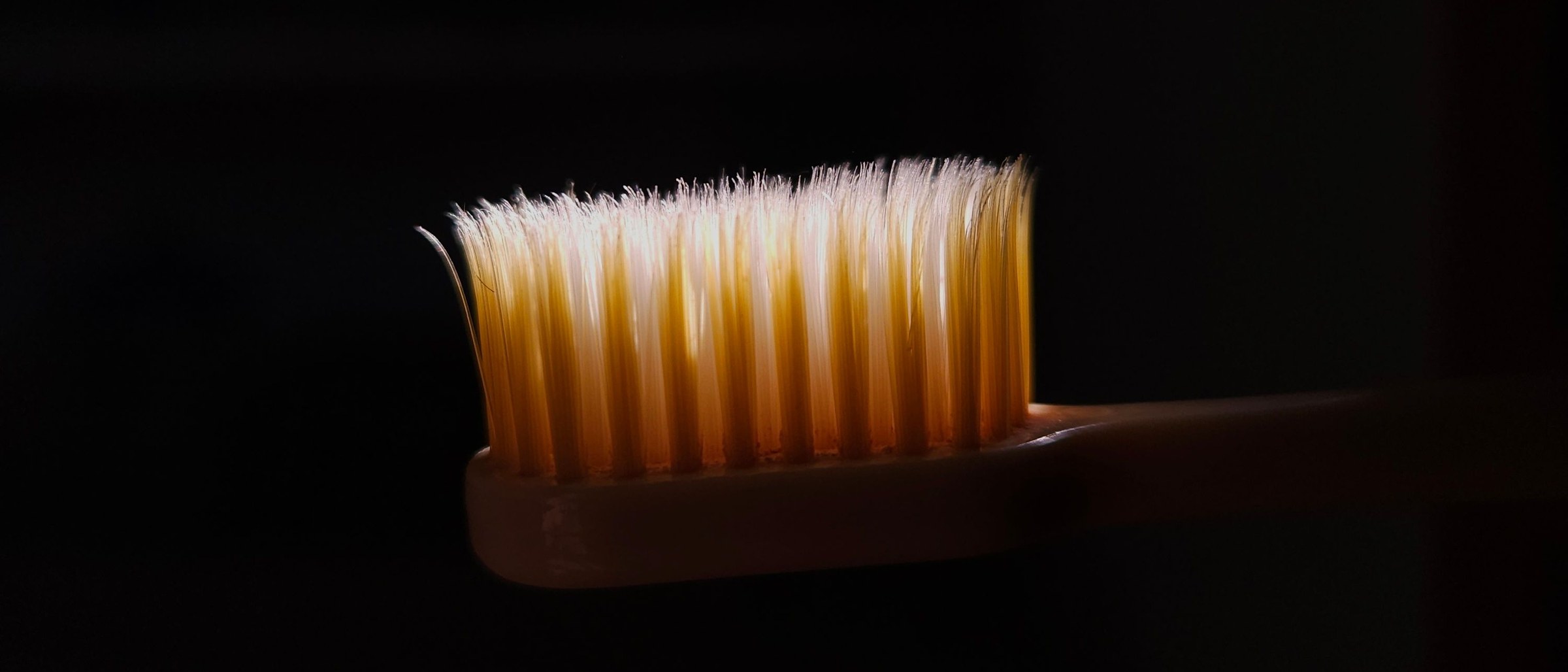 A well-used toothbrush in a single warm light.